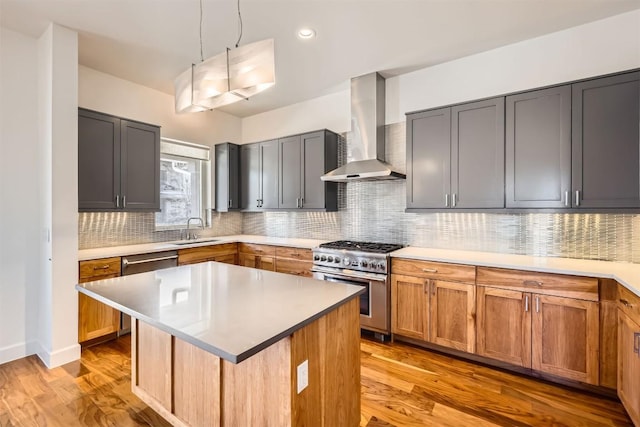 kitchen with a sink, light wood-style floors, appliances with stainless steel finishes, wall chimney exhaust hood, and backsplash