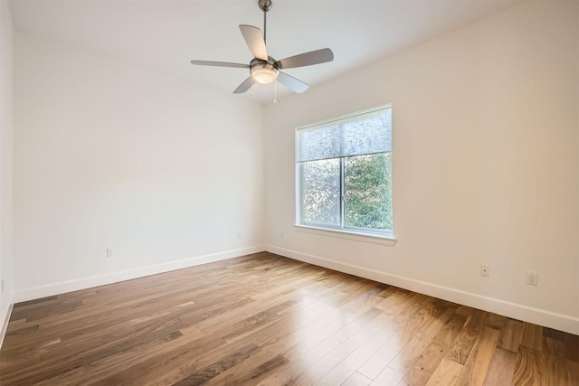 unfurnished room with baseboards, wood finished floors, and a ceiling fan