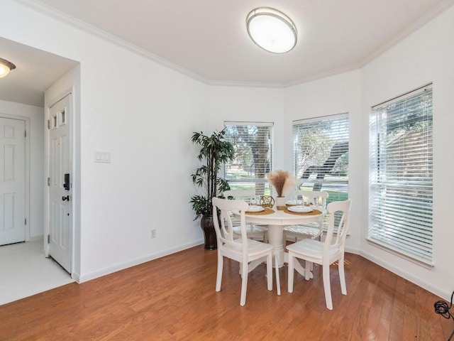 dining space with light wood finished floors, a healthy amount of sunlight, and crown molding