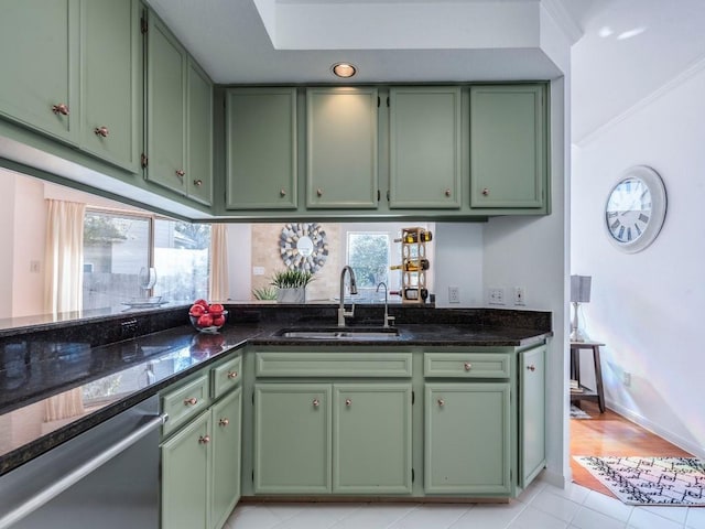 kitchen with a sink, dark stone countertops, green cabinets, dishwasher, and a healthy amount of sunlight