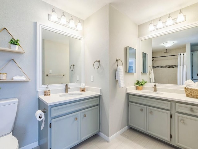 full bath featuring toilet, two vanities, and a sink