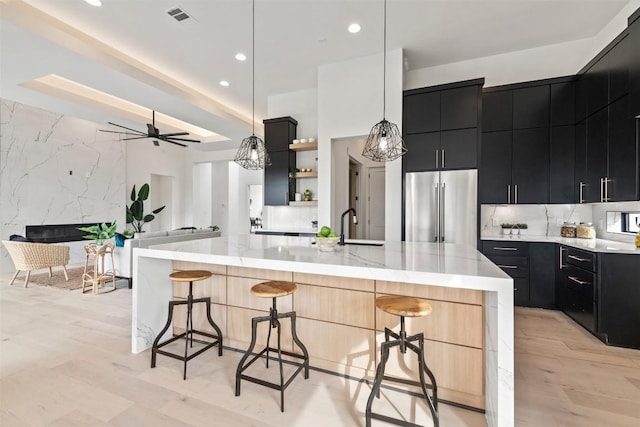 kitchen with high end refrigerator, a breakfast bar, visible vents, and dark cabinets