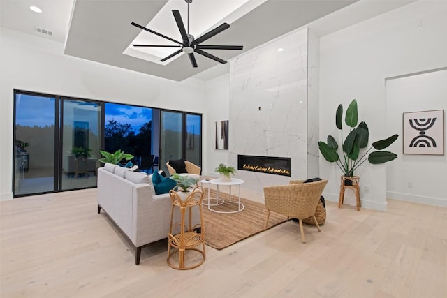 living area featuring visible vents, wood finished floors, a premium fireplace, baseboards, and ceiling fan