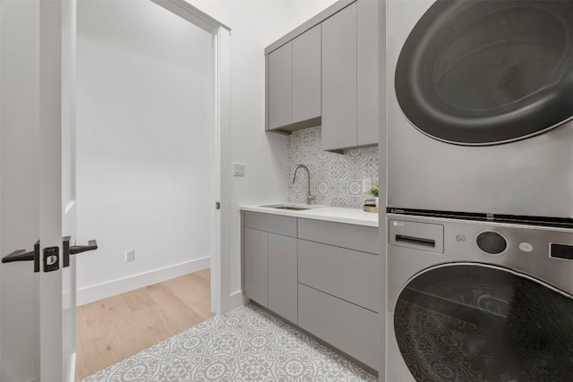 8112 Kuhn Dr, Austin, TX 78736 - washroom featuring stacked washing machine and dryer, light wood finished floors, and cabinet space