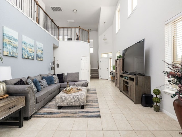 living area with light tile patterned flooring, visible vents, and a high ceiling