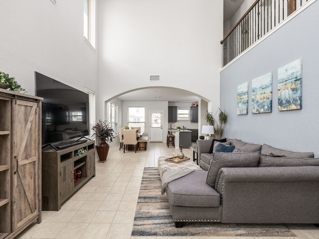 living room featuring a barn door, light tile patterned floors, arched walkways, and visible vents