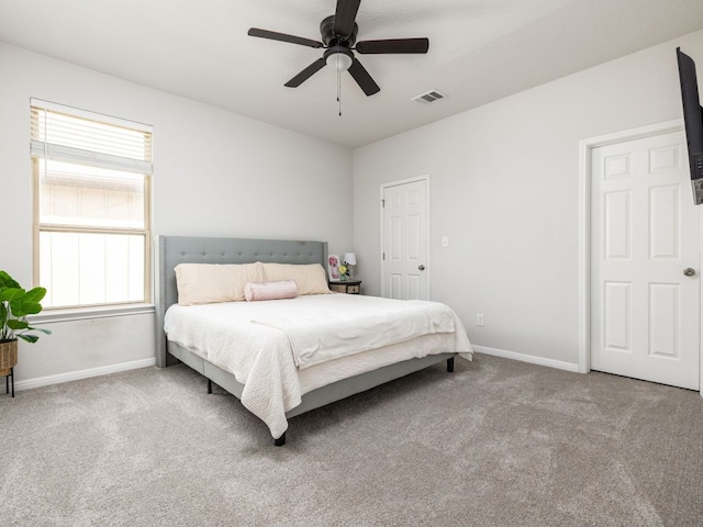 carpeted bedroom with visible vents, a ceiling fan, and baseboards