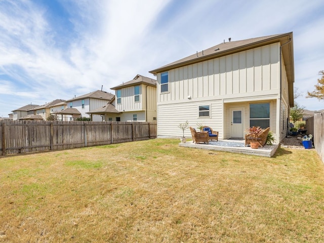 rear view of property featuring a fenced backyard, a residential view, a lawn, a patio area, and board and batten siding