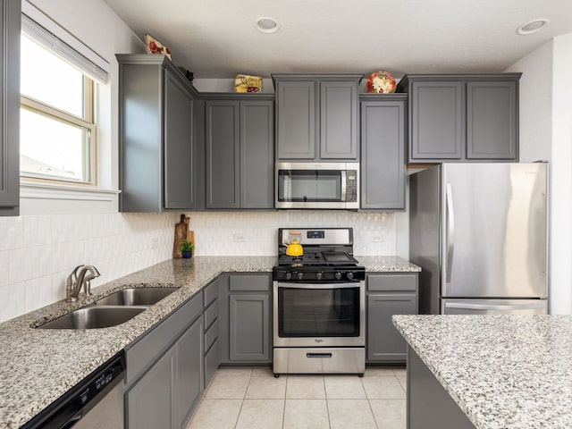 248 Brady Creek Way, Leander, TX 78641 - kitchen with stainless steel appliances, a sink, gray cabinets, light tile patterned flooring, and light stone counters