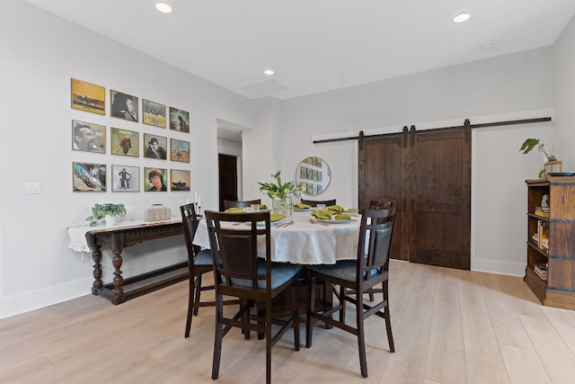 dining space with recessed lighting, a barn door, baseboards, and light wood finished floors