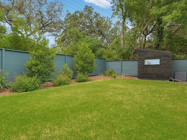 view of yard featuring a storage shed, an outbuilding, and a fenced backyard