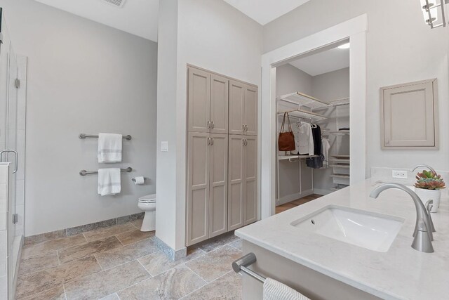 full bath with stone tile flooring, baseboards, toilet, and a stall shower