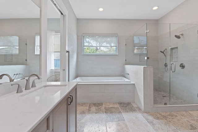 bathroom featuring stone tile floors, recessed lighting, a shower stall, a bath, and vanity