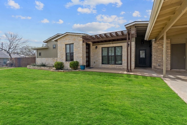 back of property featuring stone siding, a yard, and fence