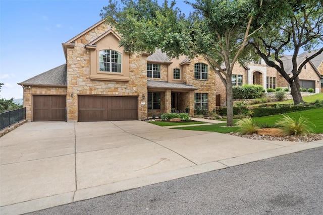 view of front of house with driveway, stone siding, a shingled roof, an attached garage, and a front yard