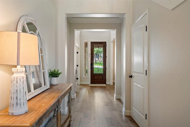 foyer with baseboards, wood finished floors, and ornamental molding