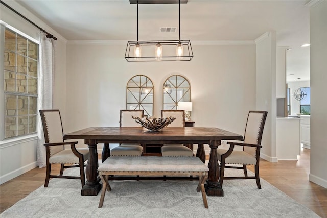 dining space with visible vents, baseboards, light wood-style floors, and ornamental molding