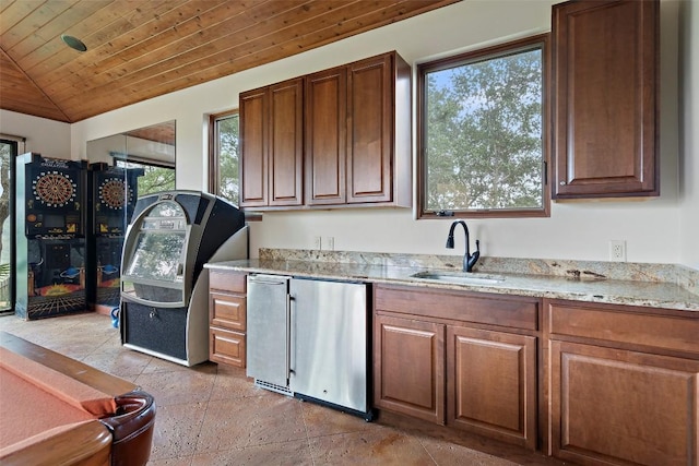 kitchen with vaulted ceiling, light stone counters, wooden ceiling, fridge, and a sink