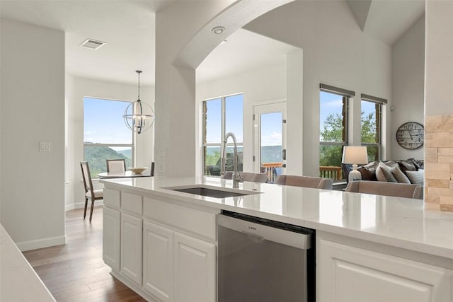 kitchen with visible vents, light wood-style flooring, a sink, arched walkways, and dishwasher