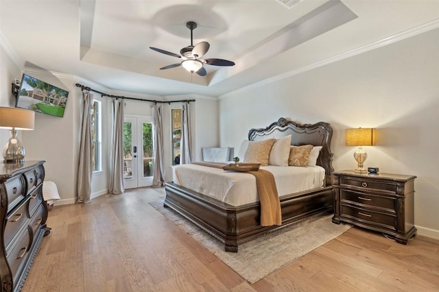 bedroom featuring a raised ceiling, light wood-style flooring, access to exterior, and baseboards