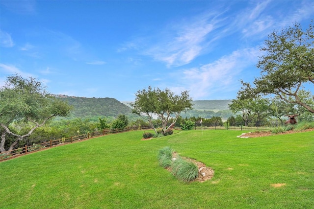 view of yard featuring a rural view, fence, and a mountain view