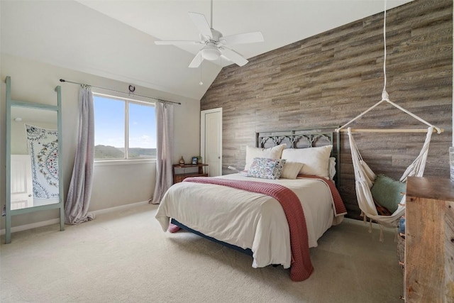 carpeted bedroom featuring wooden walls, an accent wall, baseboards, vaulted ceiling, and a ceiling fan