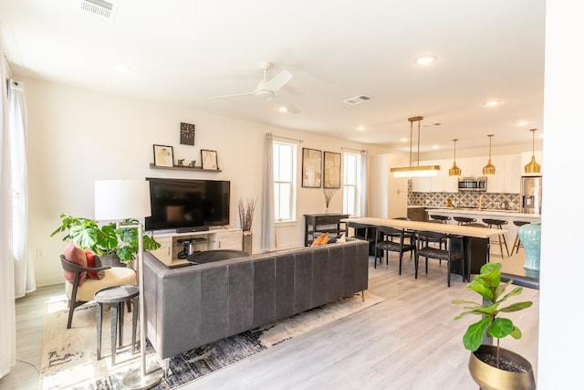 living area with light wood finished floors, visible vents, recessed lighting, and ceiling fan