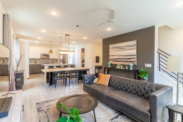 living area with recessed lighting, a ceiling fan, visible vents, and light wood finished floors