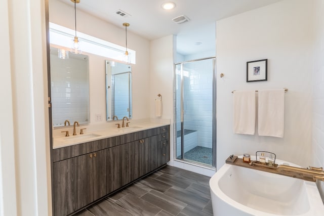 bathroom featuring a stall shower, a freestanding tub, visible vents, and a sink