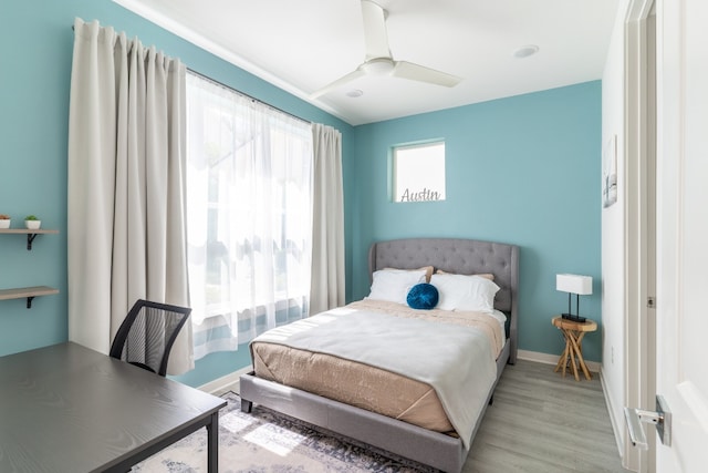 bedroom with light wood-style flooring, baseboards, and ceiling fan