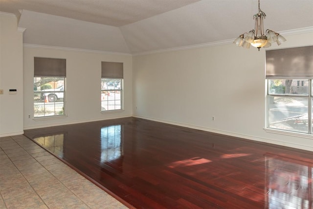 spare room with baseboards, vaulted ceiling, ornamental molding, an inviting chandelier, and wood finished floors