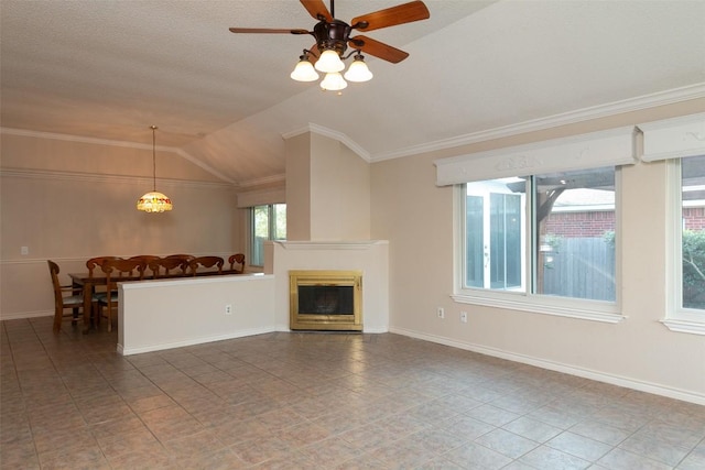 unfurnished living room featuring baseboards, ceiling fan, ornamental molding, vaulted ceiling, and a glass covered fireplace