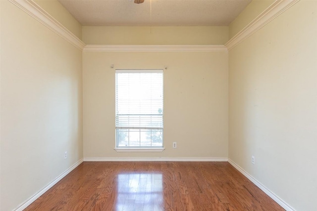 spare room with baseboards and wood finished floors