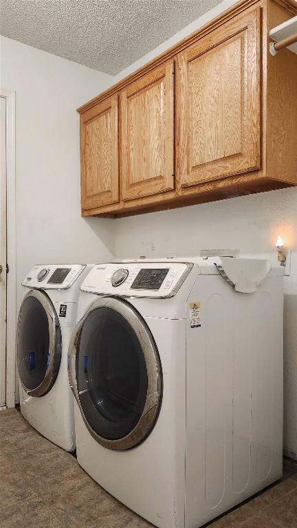 washroom with cabinet space, a textured ceiling, and washing machine and dryer