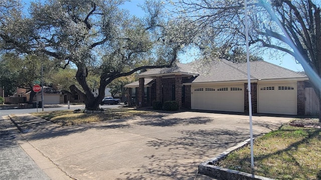 view of front of home featuring an attached garage, driveway, brick siding, and roof with shingles