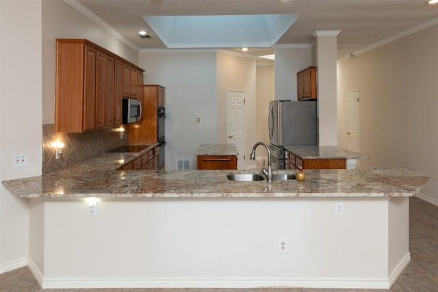 kitchen featuring backsplash, brown cabinets, a peninsula, stainless steel appliances, and a sink