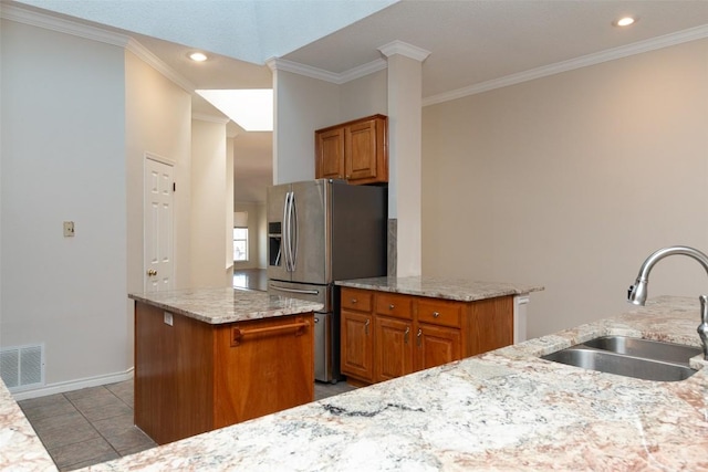 kitchen with brown cabinetry, visible vents, stainless steel refrigerator with ice dispenser, and a sink