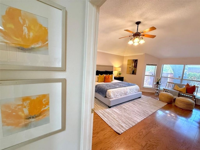 bedroom with wood finished floors, a textured ceiling, baseboards, crown molding, and a ceiling fan