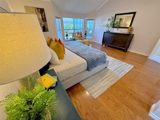 bedroom featuring lofted ceiling, wood finished floors, and baseboards