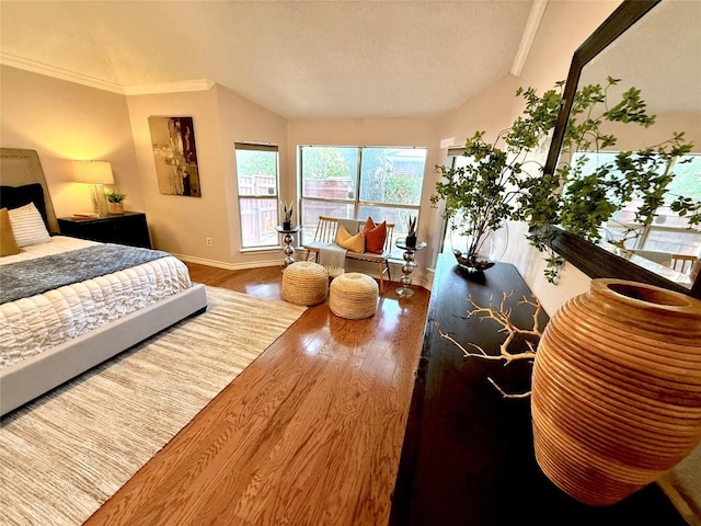 bedroom featuring lofted ceiling, wood finished floors, ornamental molding, baseboards, and a textured ceiling