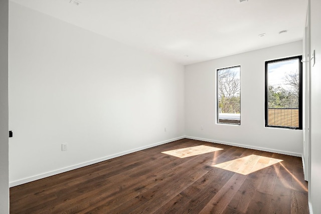 empty room featuring dark wood-type flooring and baseboards