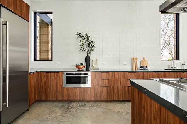 kitchen with dark countertops, brown cabinetry, modern cabinets, and stainless steel appliances