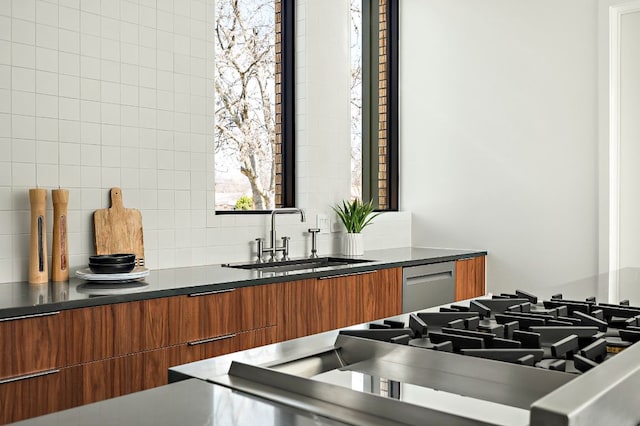 kitchen featuring brown cabinets, modern cabinets, a sink, dark countertops, and decorative backsplash