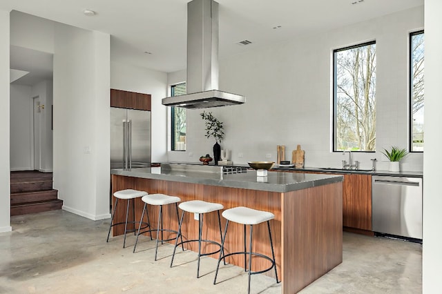 kitchen with island exhaust hood, stainless steel appliances, concrete floors, and modern cabinets