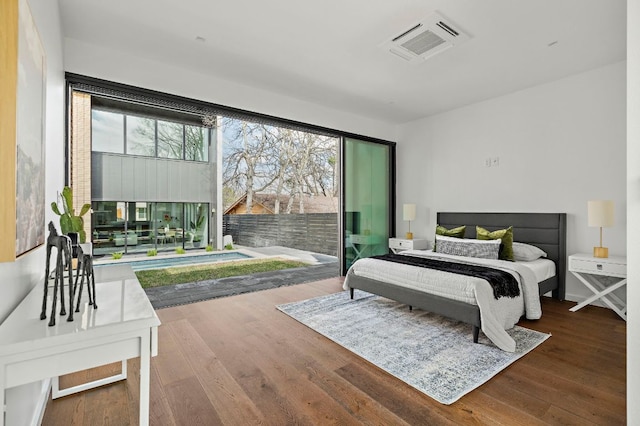 bedroom with access to outside, wood finished floors, and visible vents