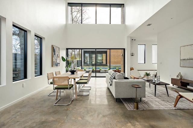 living room with a wealth of natural light, visible vents, baseboards, and finished concrete floors