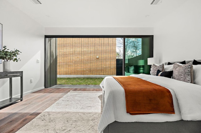 bedroom with visible vents, wood finished floors, and baseboards