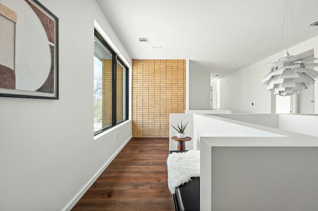 hallway featuring visible vents, baseboards, and dark wood-style floors