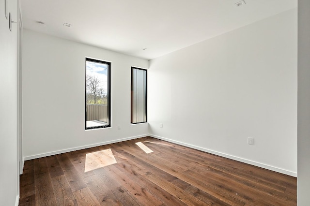 unfurnished room featuring baseboards and dark wood-style flooring