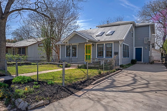 view of front of house featuring a fenced front yard, metal roof, driveway, and a standing seam roof